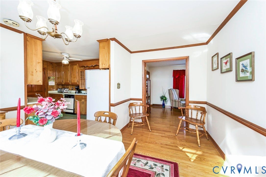 700 Lakeside Drive, Emporia, Emporia, VA 23847 Dining area featuring wood-finish flooring, chair rail molding, and a multi-arm chandelier, encompassing a kitchen with wood cabinetry and a ceiling fan