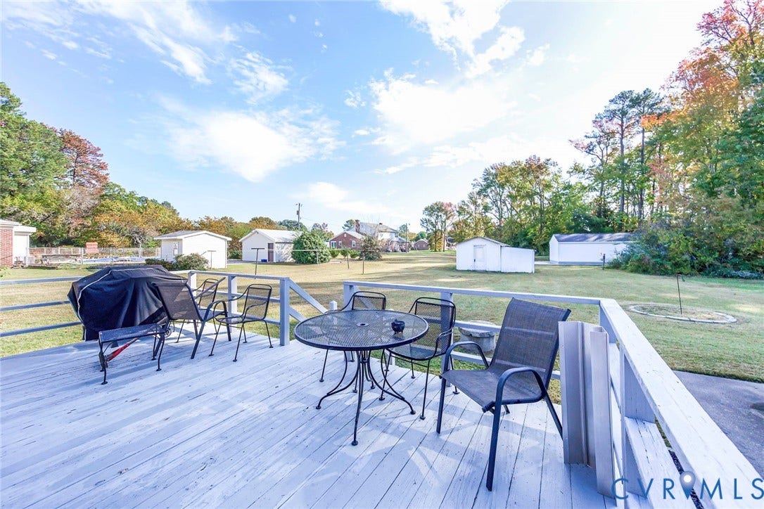 700 Lakeside Drive, Emporia, Emporia, VA 23847 Elevated wooden deck featuring a railed perimeter, opening to an expansive backyard with mature trees and multiple detached utility structures