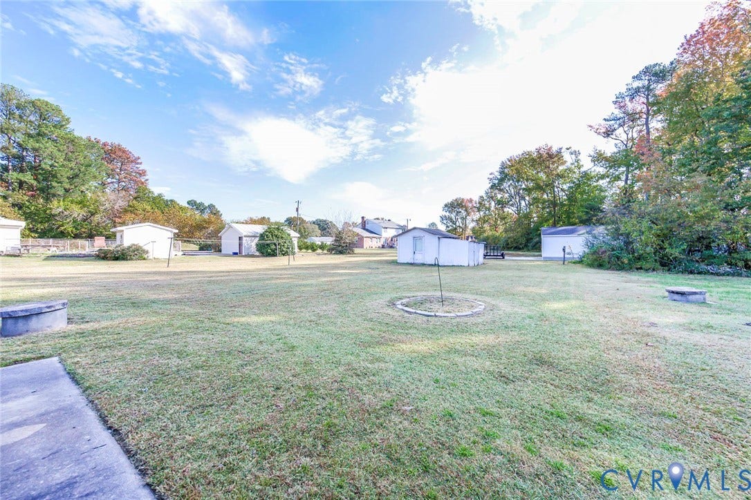 700 Lakeside Drive, Emporia, Emporia, VA 23847 Expansive lot featuring a wide grassy expanse, mature trees, concrete perimeter structures, and multiple detached outbuildings