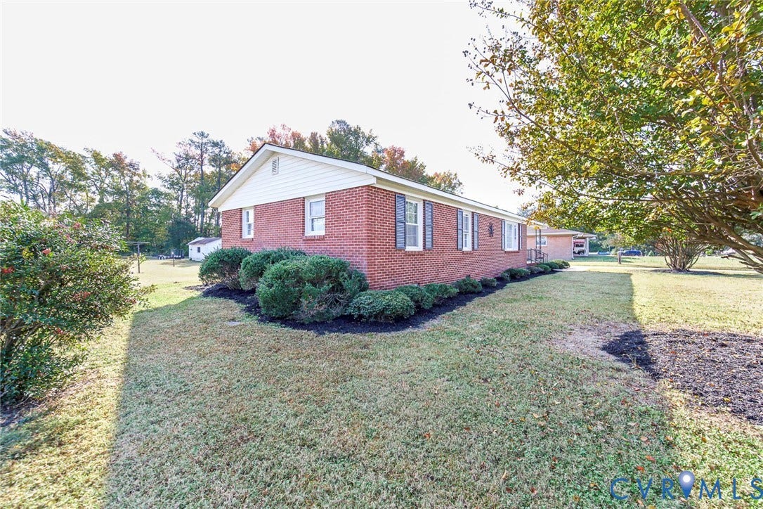 700 Lakeside Drive, Emporia, Emporia, VA 23847 Brick exterior featuring a gabled roofline, light-toned horizontal siding, dark window shutters, and manicured foundation landscaping