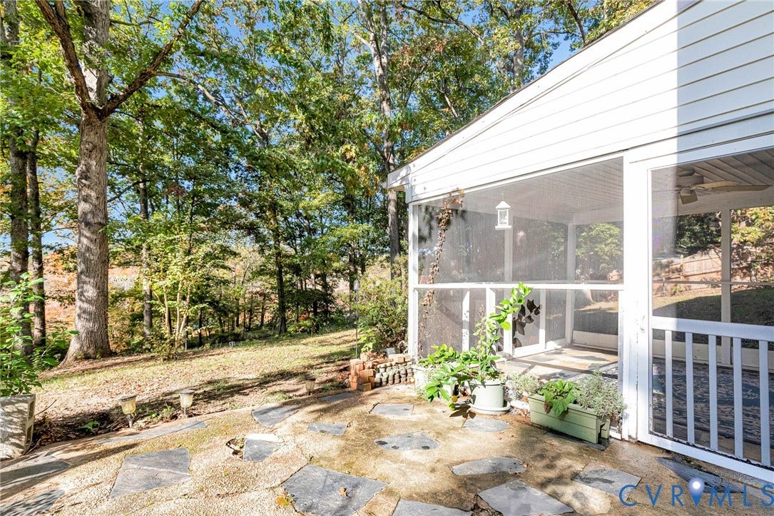 1526 Westshire Lane, Henrico, VA 23238 Flagstone patio featuring an integrated screen porch with white railing, ceiling fan, and surrounding mature wooded backdrop