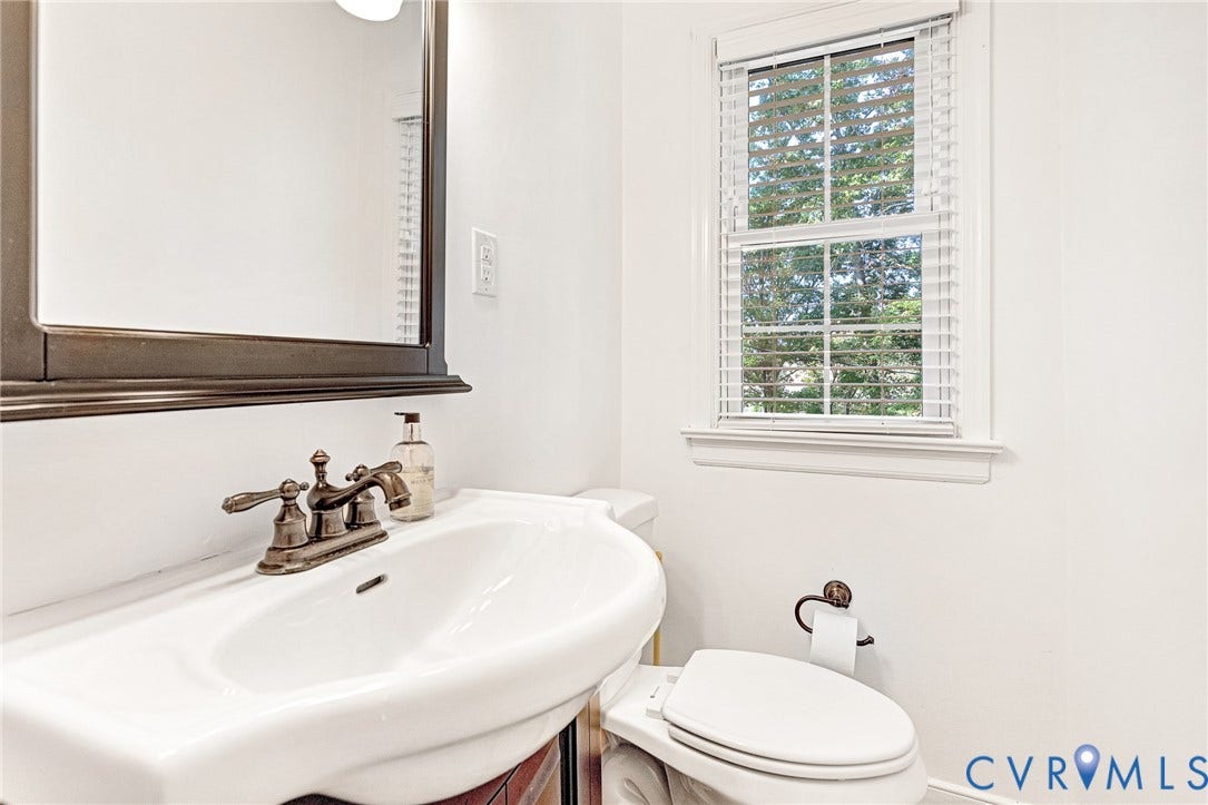 1526 Westshire Lane, Henrico, VA 23238 Wall-mounted mirror with a dark wood-finish frame, pedestal sink with a bronze-toned widespread faucet, and matching bronze-toned hardware