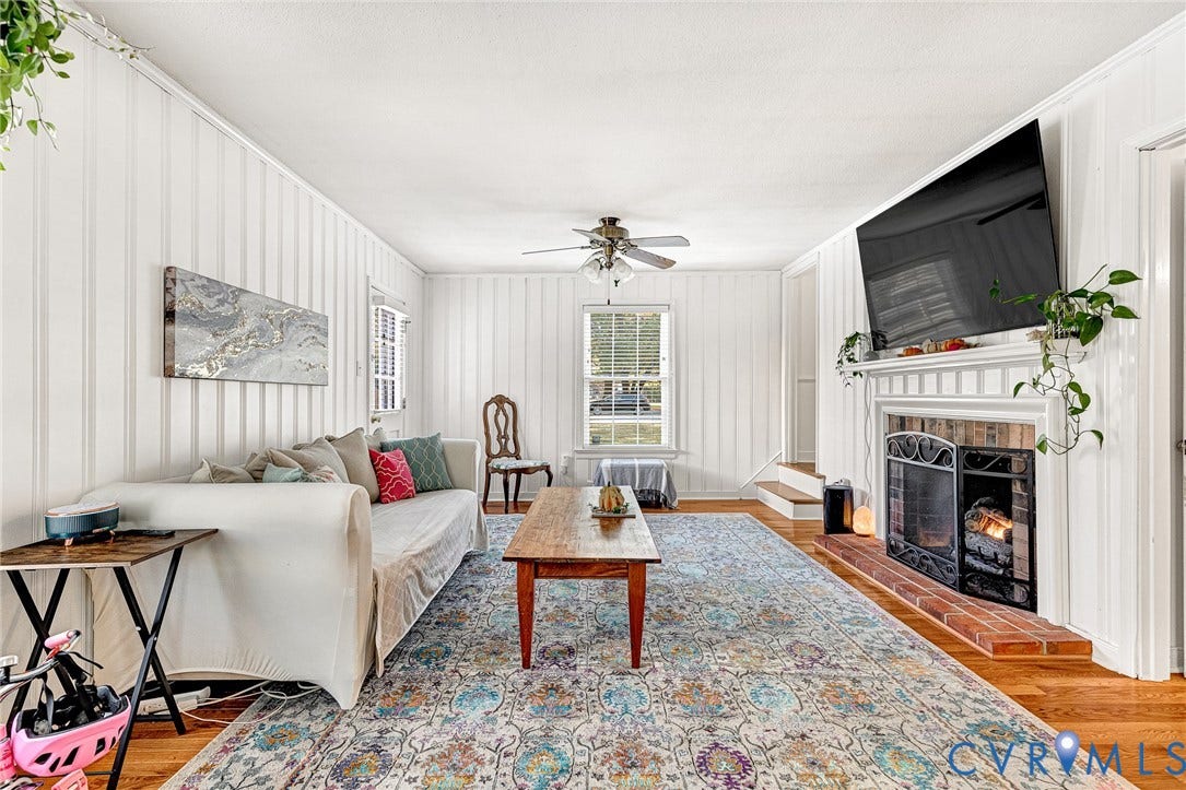 1526 Westshire Lane, Henrico, VA 23238 Living area featuring vertical plank wall paneling, wood-finish flooring, a wood-burning fireplace with a brick hearth, and a ceiling fan