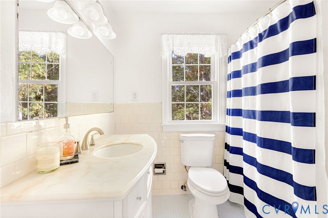 1526 Westshire Lane, Henrico, VA 23238 Vanity with a solid surface countertop, integrated sink, polished metal faucet, subway tile wainscoting, and large wall-mounted mirror