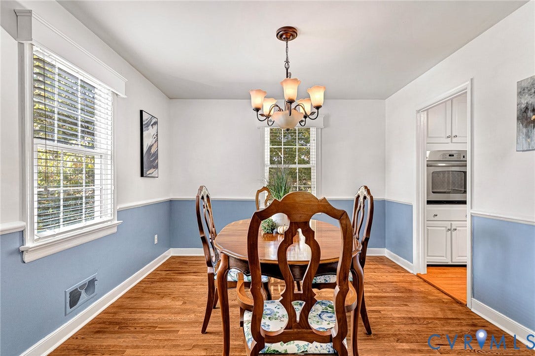 1526 Westshire Lane, Henrico, VA 23238 Dining area featuring wood-finish flooring, two-tone wall paint with chair rail molding, multi-light chandelier, and double-hung windows