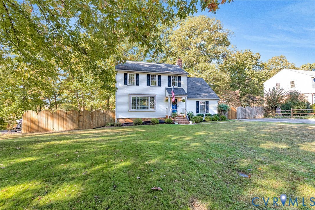 1526 Westshire Lane, Henrico, VA 23238 Two-story traditional exterior featuring white lap siding, dark shutters, a front gabled entryway, a masonry chimney, and a picket-style wood privacy fence