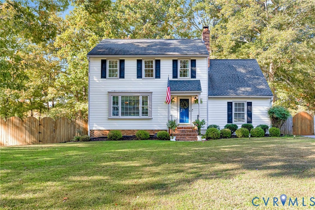 1526 Westshire Lane, Henrico, VA 23238 Two-story Colonial exterior featuring light siding, dark shutter accents, a brick front stoop, and a wood-slat privacy fence