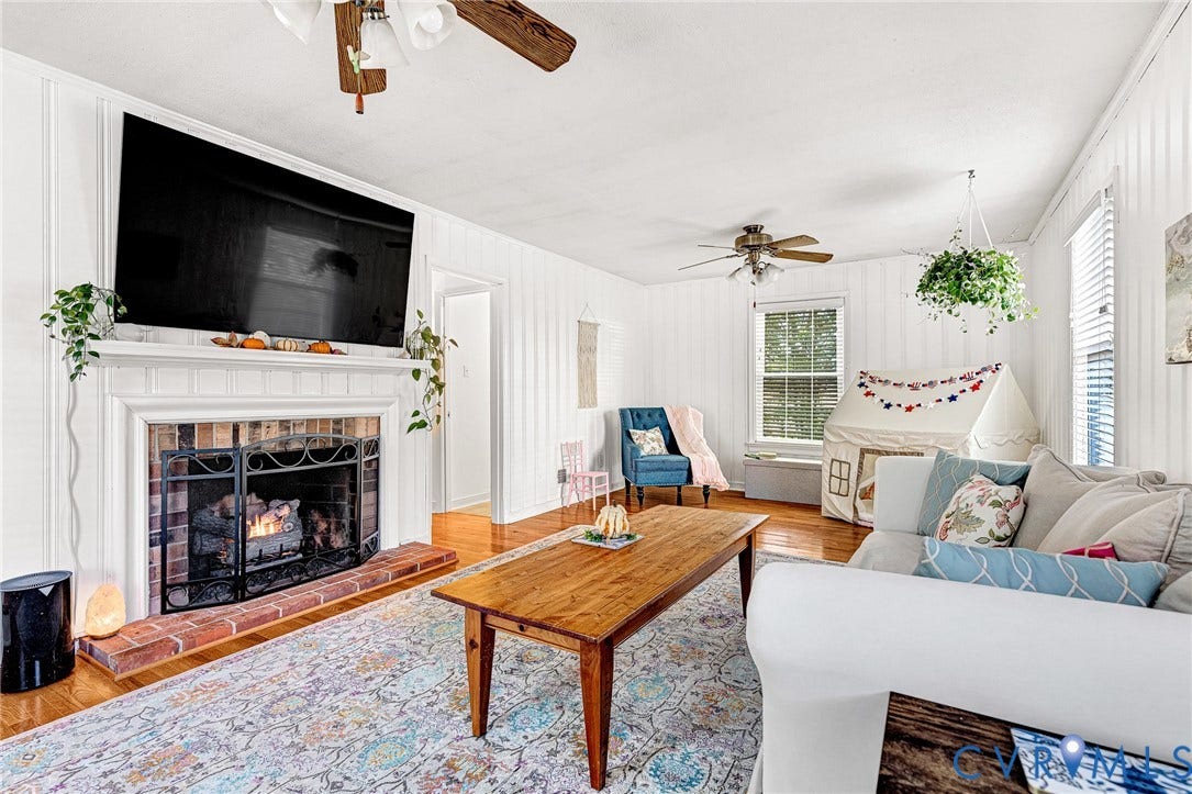 1526 Westshire Lane, Henrico, VA 23238 Living space featuring wood-finish flooring, vertical panel wall detailing, and a brick-surround fireplace with a classic white mantel
