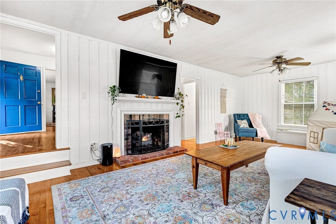 1526 Westshire Lane, Henrico, VA 23238 Living area featuring vertical plank wall paneling, a fireplace with a brick hearth, wood-finish flooring, and dual ceiling fans