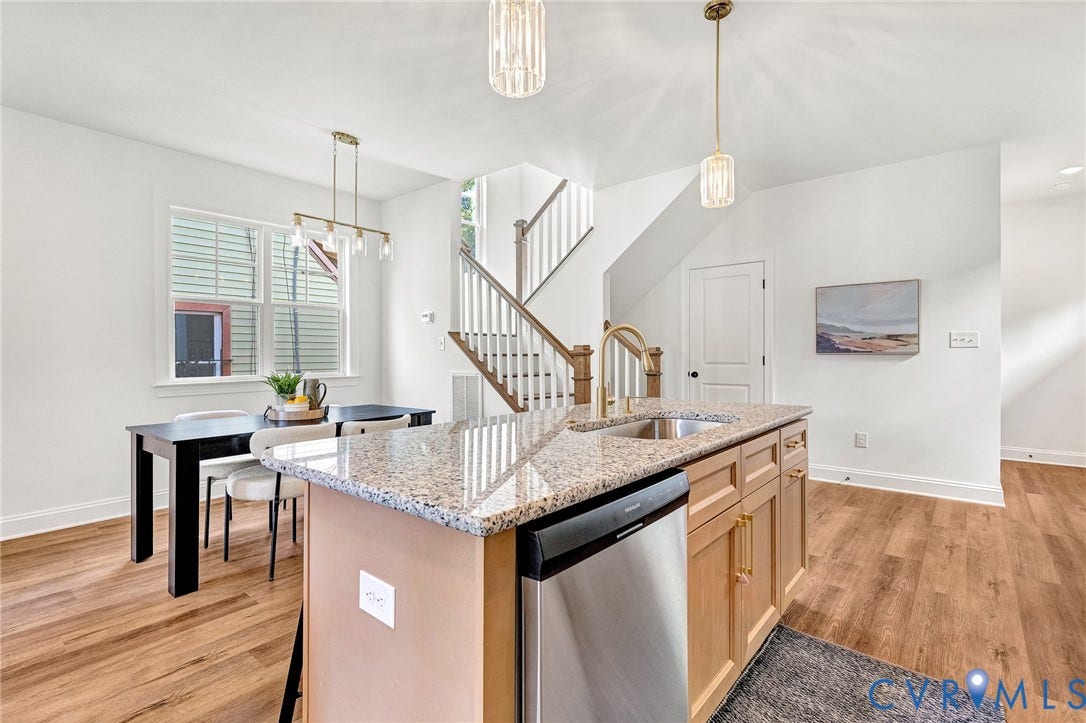 1807.5 Gordon Avenue, Oak Grove, Oak Grove, VA 23224 Kitchen island featuring stone countertops, a stainless steel dishwasher, and a faucet, complemented by wood-finish flooring, two pendant lights, and a wooden staircase with balusters