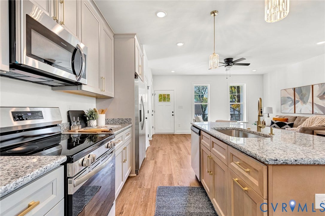 1807.5 Gordon Avenue, Oak Grove, Oak Grove, VA 23224 Kitchen featuring stainless steel appliances, speckled stone countertops, wood-finish flooring, shaker-style cabinetry with brass-tone hardware, and an island with an undermount sink