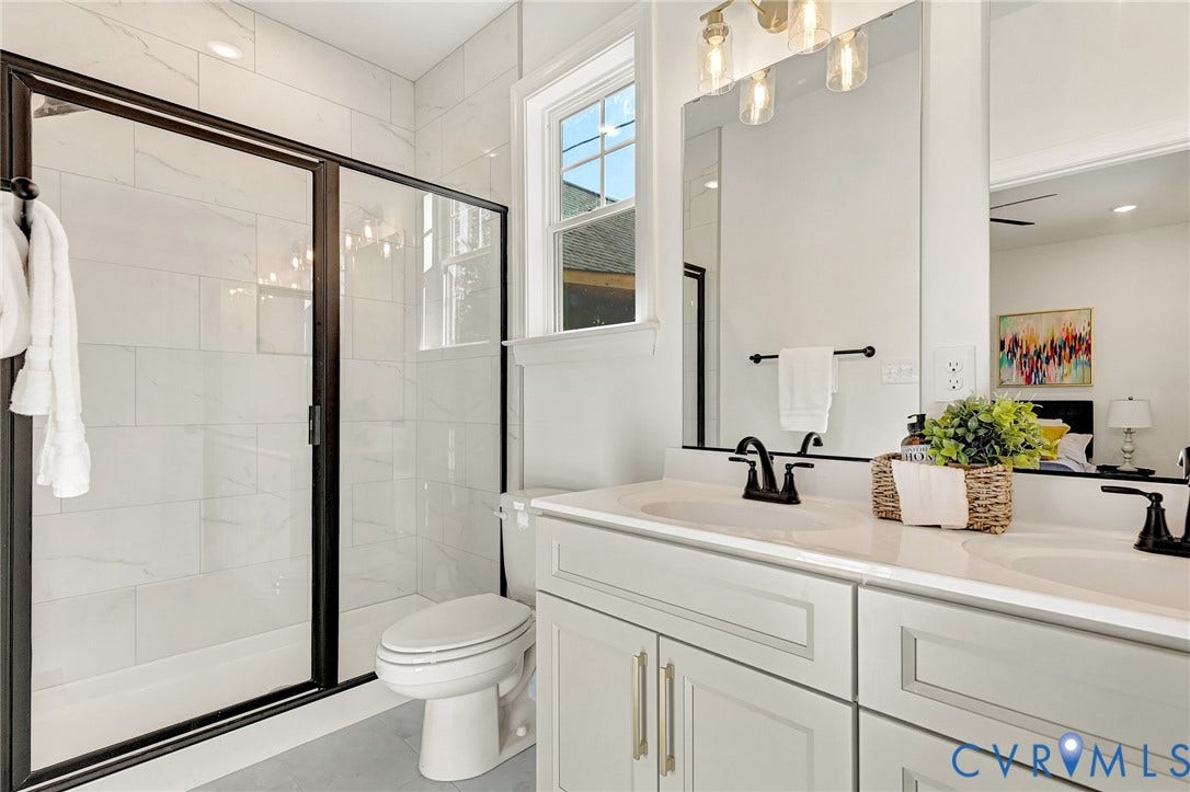 1807.5 Gordon Avenue, Oak Grove, Oak Grove, VA 23224 Double vanity with stone-composite countertop, light-toned shaker cabinetry, matte black hardware, and a walk-in shower featuring glass doors with black framing and light-toned tile surround