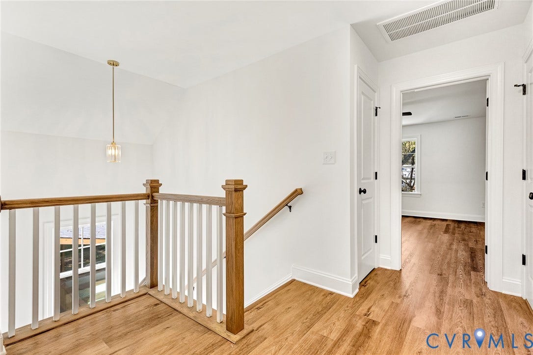 1807.5 Gordon Avenue, Oak Grove, Oak Grove, VA 23224 Landing featuring wood-finish flooring, a wood and white spindle balustrade, a singular brass-toned pendant light, and interior doors with black hardware