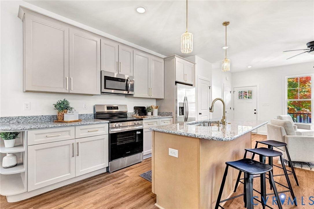 1807.5 Gordon Avenue, Oak Grove, Oak Grove, VA 23224 Kitchen featuring light-toned cabinetry, stone-surface countertops, stainless steel appliances, a central island with a sink, and wood-finish flooring