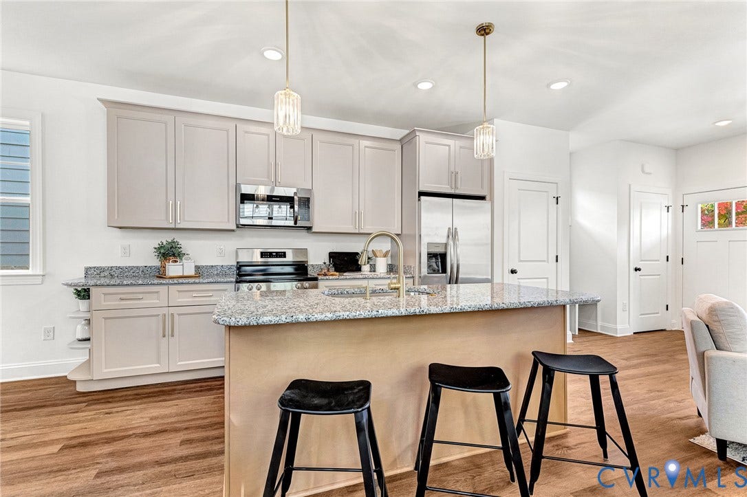 1807.5 Gordon Avenue, Oak Grove, Oak Grove, VA 23224 Kitchen featuring cabinetry with brushed nickel hardware, stone-composite countertops, stainless steel appliances, a center island with a faucet, and wood-finish flooring