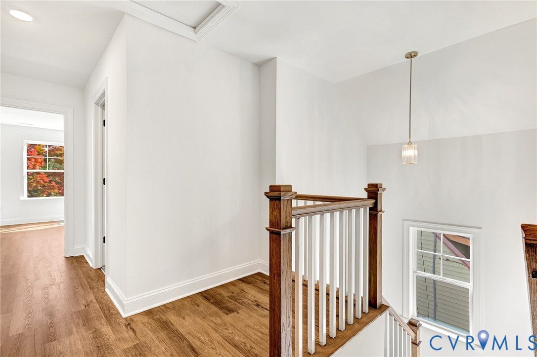 1807.5 Gordon Avenue, Oak Grove, Oak Grove, VA 23224 Landing area featuring wood-finish flooring, a classic staircase with a wood handrail, white balusters, multi-pane windows, and a singular pendant light fixture