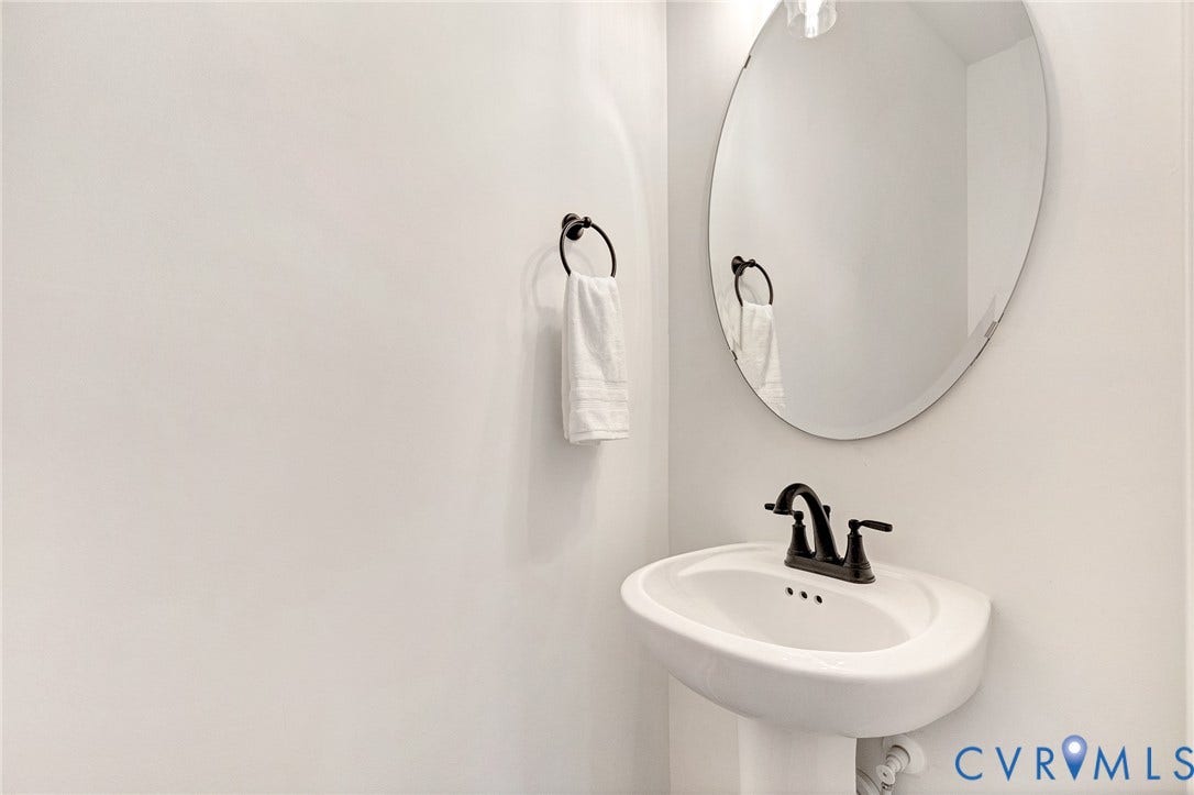 1807.5 Gordon Avenue, Oak Grove, Oak Grove, VA 23224 Pedestal sink with a dark-finish widespread faucet, oval mirror, and circular towel ring