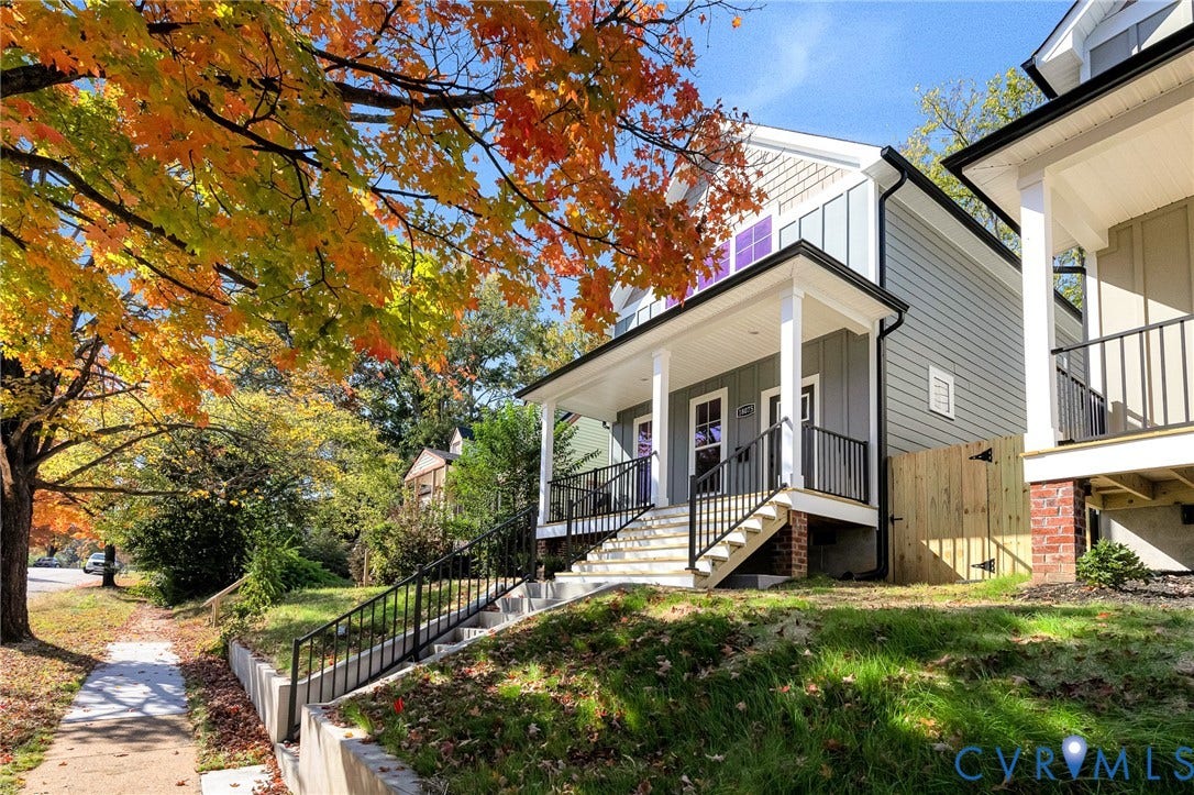 1807.5 Gordon Avenue, Oak Grove, Oak Grove, VA 23224 Elevated residence featuring vertical board-and-batten siding, a covered front porch with black metal railings, and concrete entry stairs