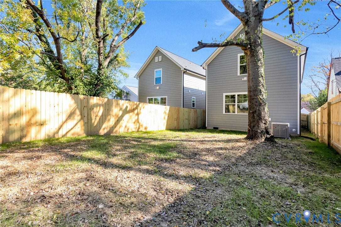 1807.5 Gordon Avenue, Oak Grove, Oak Grove, VA 23224 Rear yard featuring horizontal wood privacy fencing, mature trees, and grey lap siding exterior