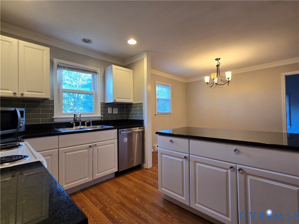 Kitchen featuring white cabinetry, dark stone countertops, subway tile backsplash, stainless steel appliances, and wood-finish flooring