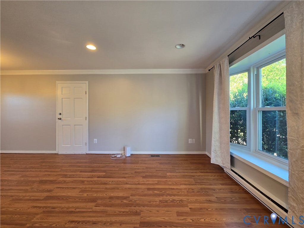 Living space featuring wood-finish flooring, a multi-pane bay window, crown molding, and recessed lighting