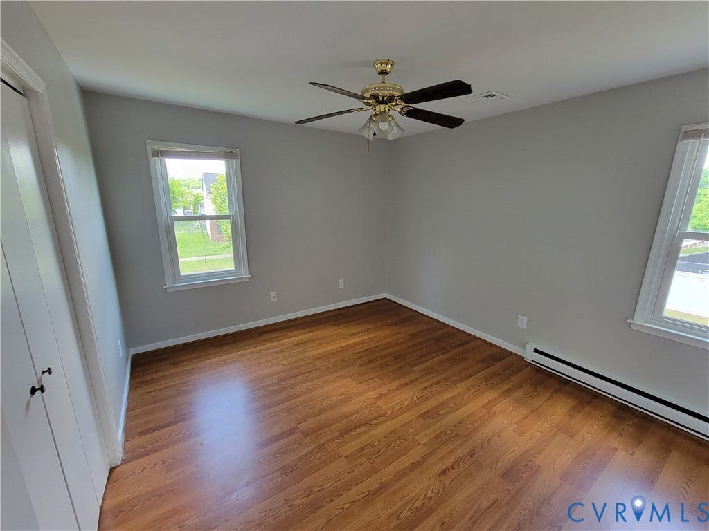 Wood-finish flooring, dual windows, and a ceiling fan with integrated lighting