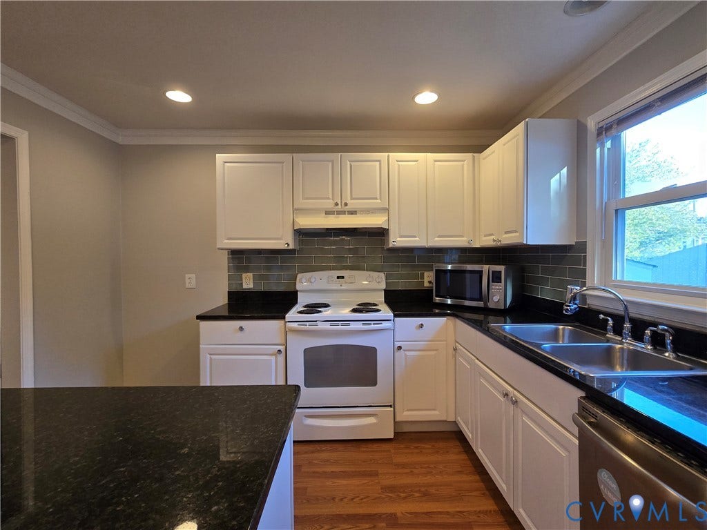 Kitchen featuring white cabinetry, dark stone countertops, grey subway tile backsplash, stainless steel sink with a goose-neck faucet, and wood-finish flooring