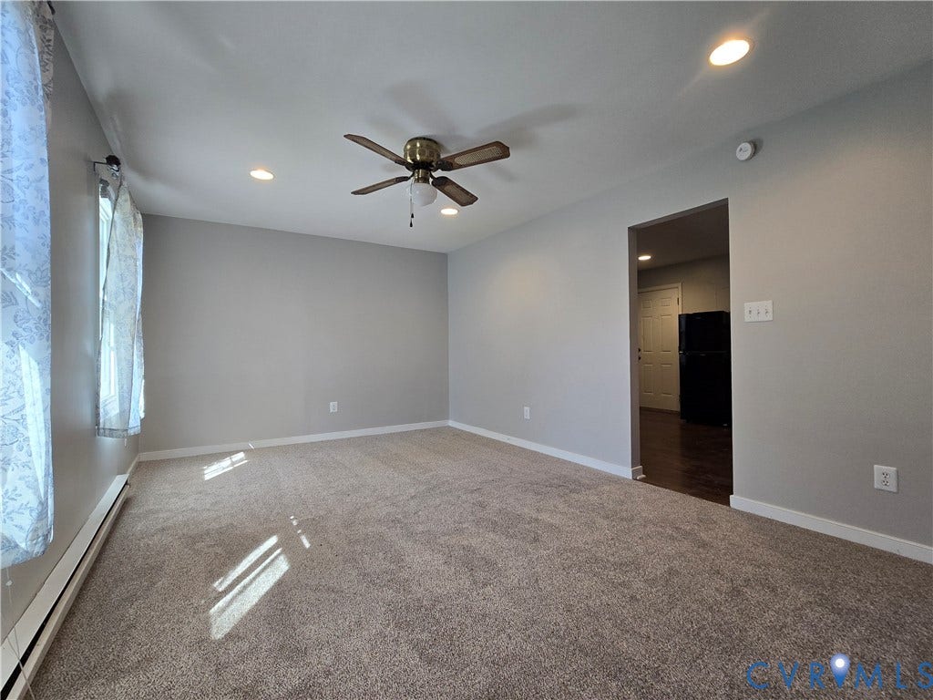 Neutral wall coloring, wall-to-wall carpeting, recessed lighting, and a ceiling fan with integrated light fixture