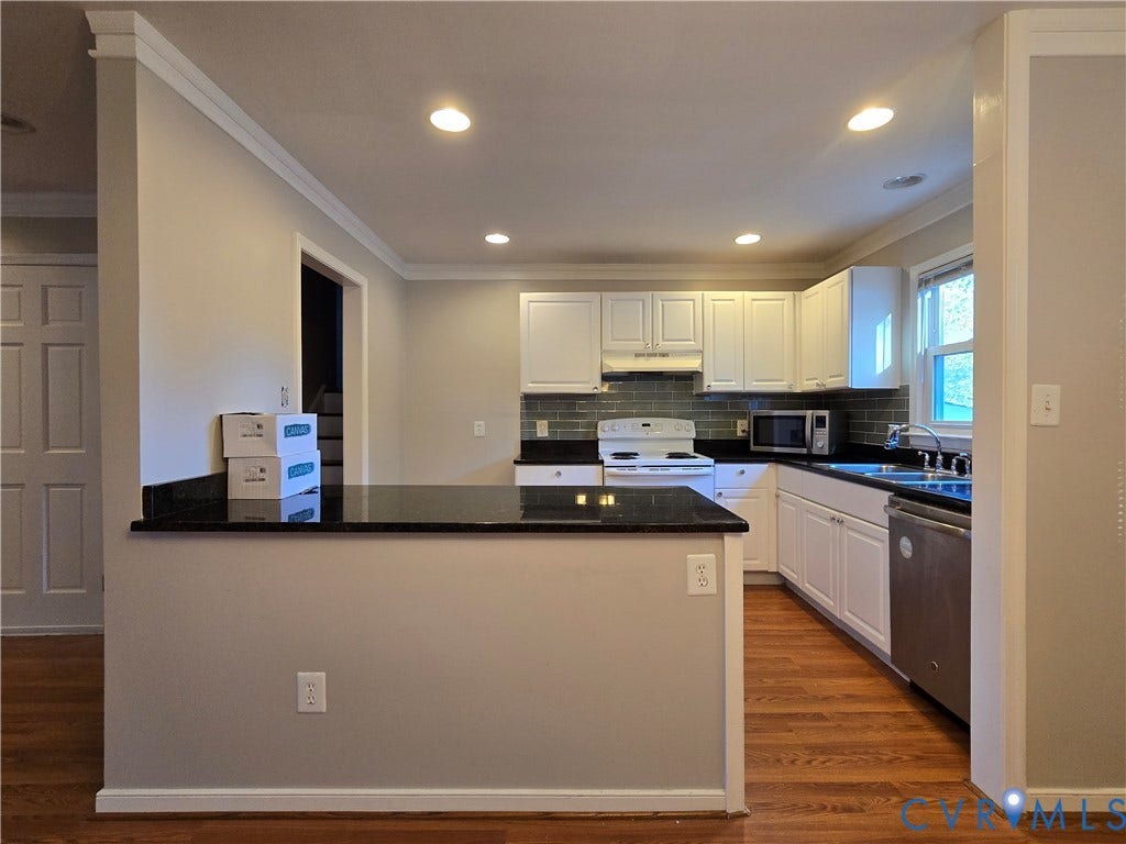 Kitchen featuring white cabinetry, dark stone countertops, subway tile backsplash, stainless steel dishwasher, and wood-finish flooring