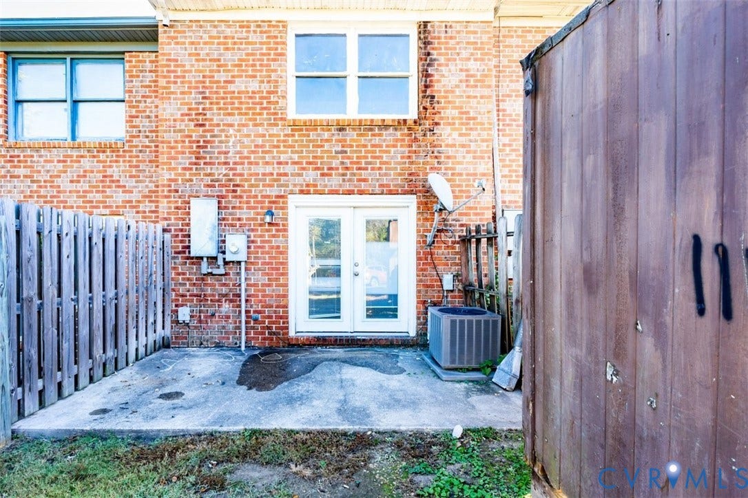 2358 Hill Street, #G, Petersburg, VA 23803 Exterior red brick facade featuring a concrete patio, white-framed French doors, and wood-style privacy fencing