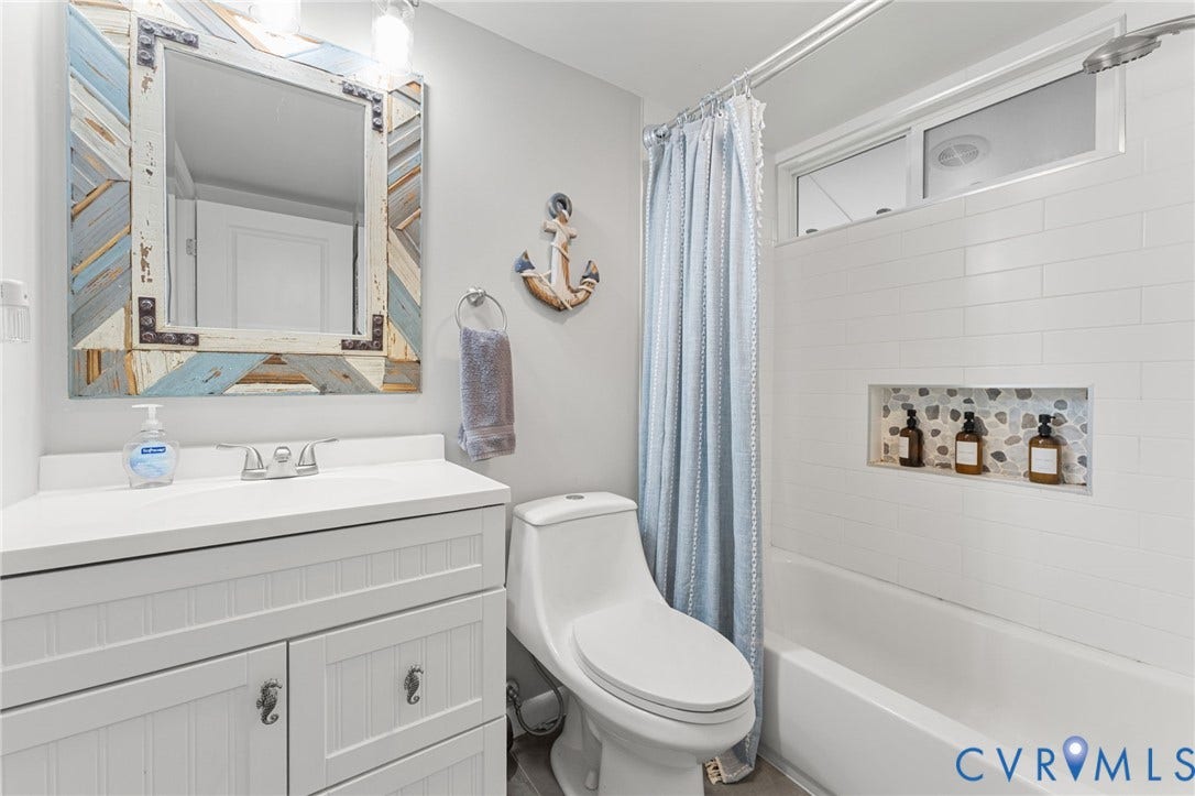 Bathroom featuring a white vanity with beadboard detailing, a rectangular basin, a tub-shower combination with white subway tile surround, and a recessed stone-tiled shower niche