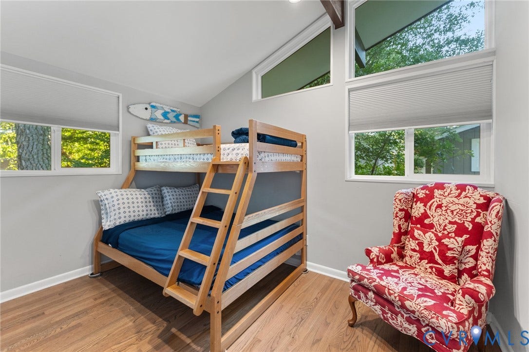 Vaulted ceilings featuring exposed wood-finish beams, large trapezoidal windows, and wood-finish flooring