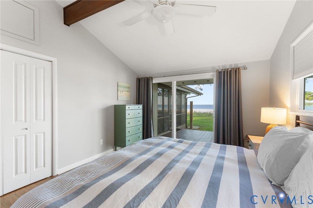 Vaulted ceiling with exposed wood-finish beam, ceiling fan, and sliding glass door with access to a covered outdoor space
