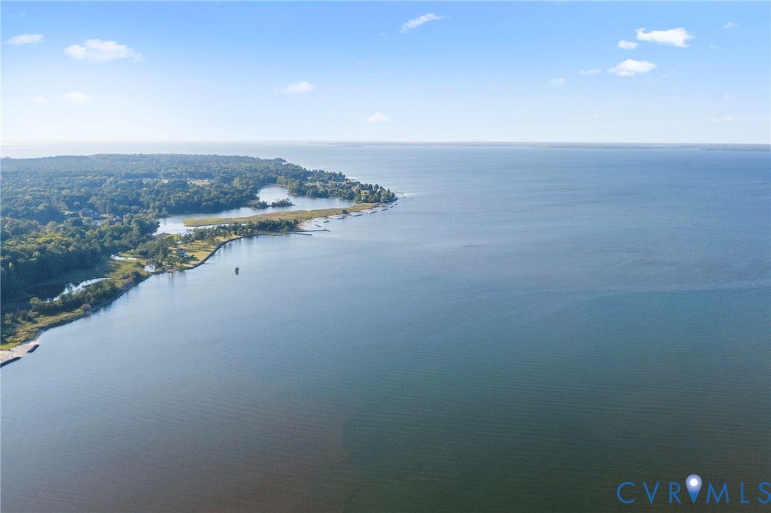 Aerial perspective of waterfront parcel featuring extensive shoreline, natural woodland, and direct access to open water