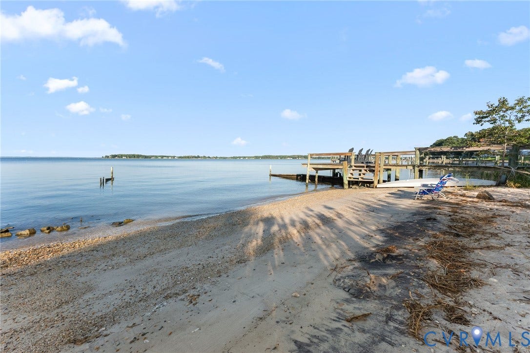 Private sandy shoreline featuring an expansive wooden pier and open water access