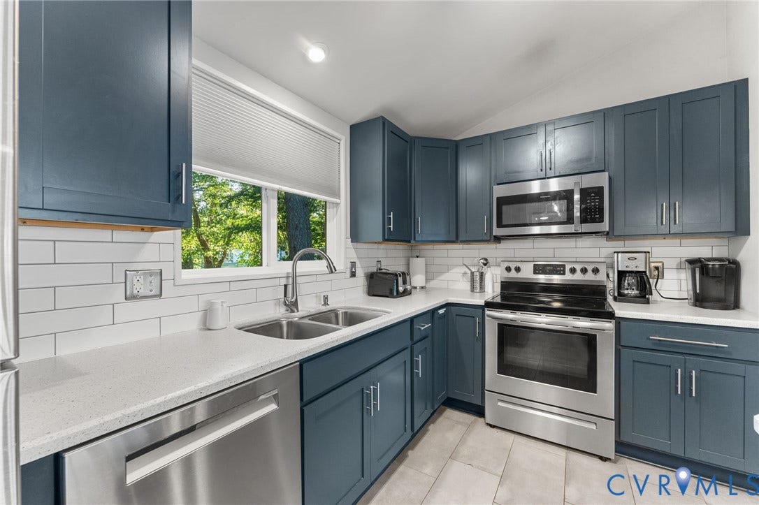 Kitchen featuring navy blue shaker cabinetry, white quartz countertops, white subway tile backsplash, stainless steel appliances, and tile flooring