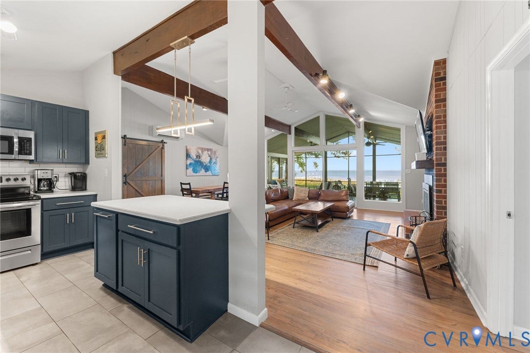Open-concept kitchen featuring navy blue cabinetry, quartz countertops, and a modern pendant light