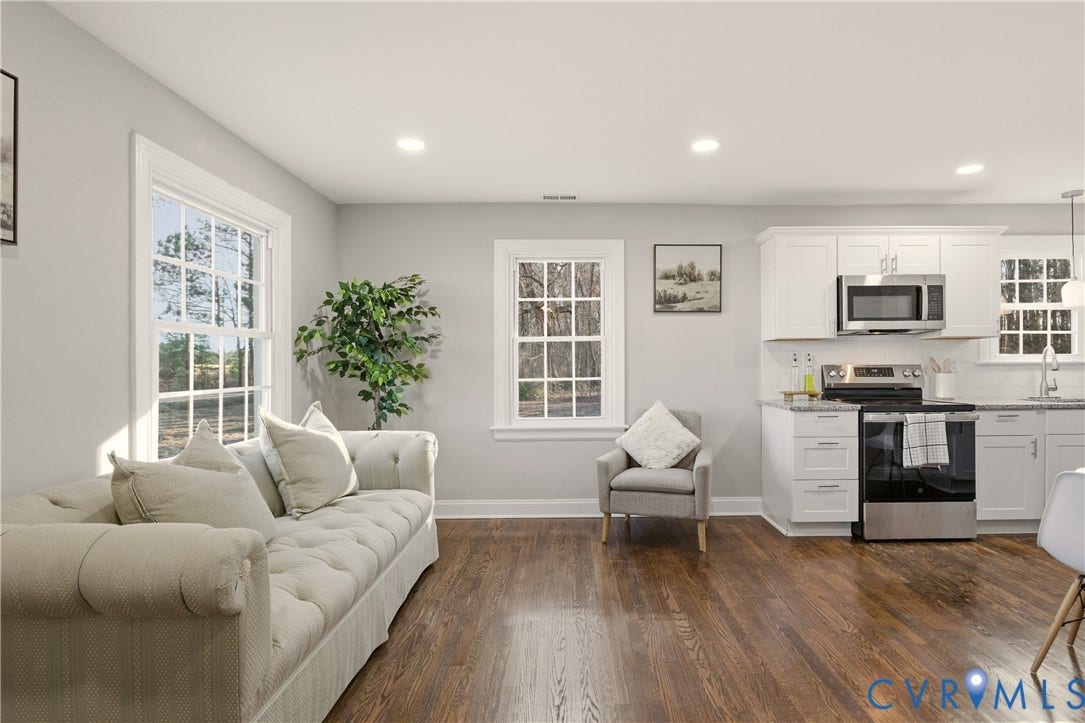 6280 Monahan Road, Henrico, VA 23231 Open-concept interior featuring wood-finish flooring, white shaker-style cabinetry, stainless steel appliances, and multi-pane windows
