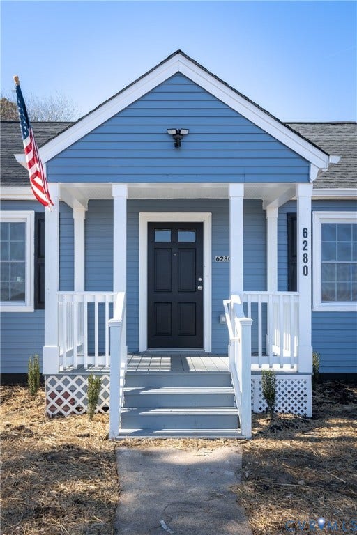 6280 Monahan Road, Henrico, VA 23231 Front exterior featuring blue horizontal siding, white trim, a covered porch with white railing, lattice skirting, and a dark multi-panel entry door
