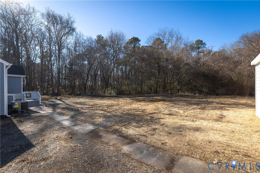 6280 Monahan Road, Henrico, VA 23231 Expansive backyard featuring a concrete walkway, elevated wood-finish entry platform, and mature trees