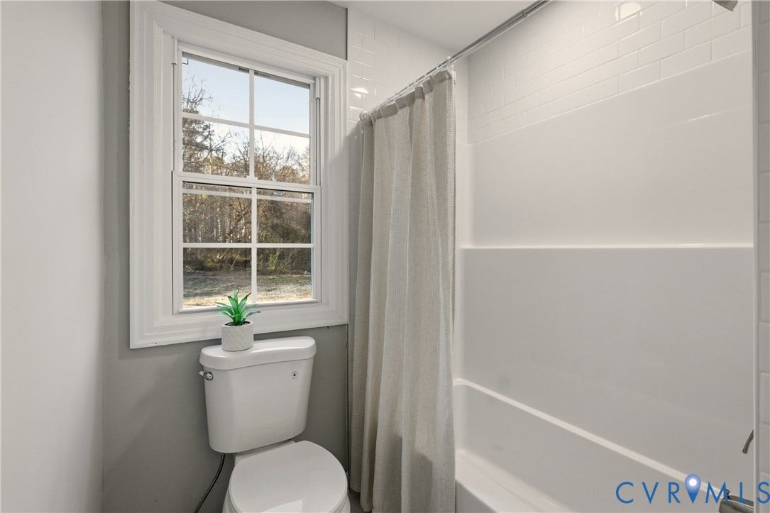 6280 Monahan Road, Henrico, VA 23231 Bathroom featuring a white tub-and-shower combination, wall-mounted white subway tile, a dual-pane window, and a white toilet