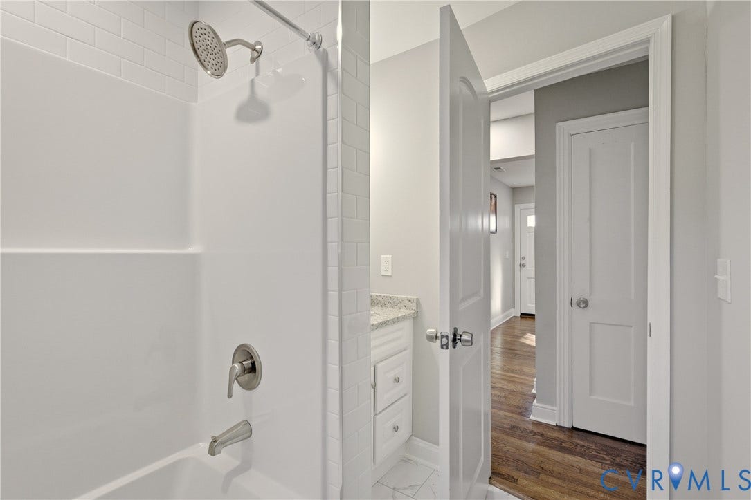 6280 Monahan Road, Henrico, VA 23231 Bathtub with a shower head, subway-tile surround, stone-finish vanity countertop, and wood-finish flooring