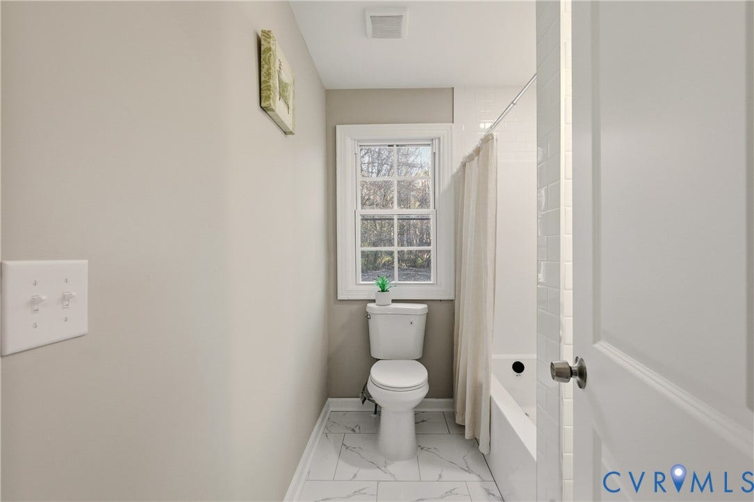 6280 Monahan Road, Henrico, VA 23231 Bathroom featuring white subway tile wall surround, tub with chrome hardware, dual-pane window with muntins, and large-format tile flooring with a neutral veined pattern