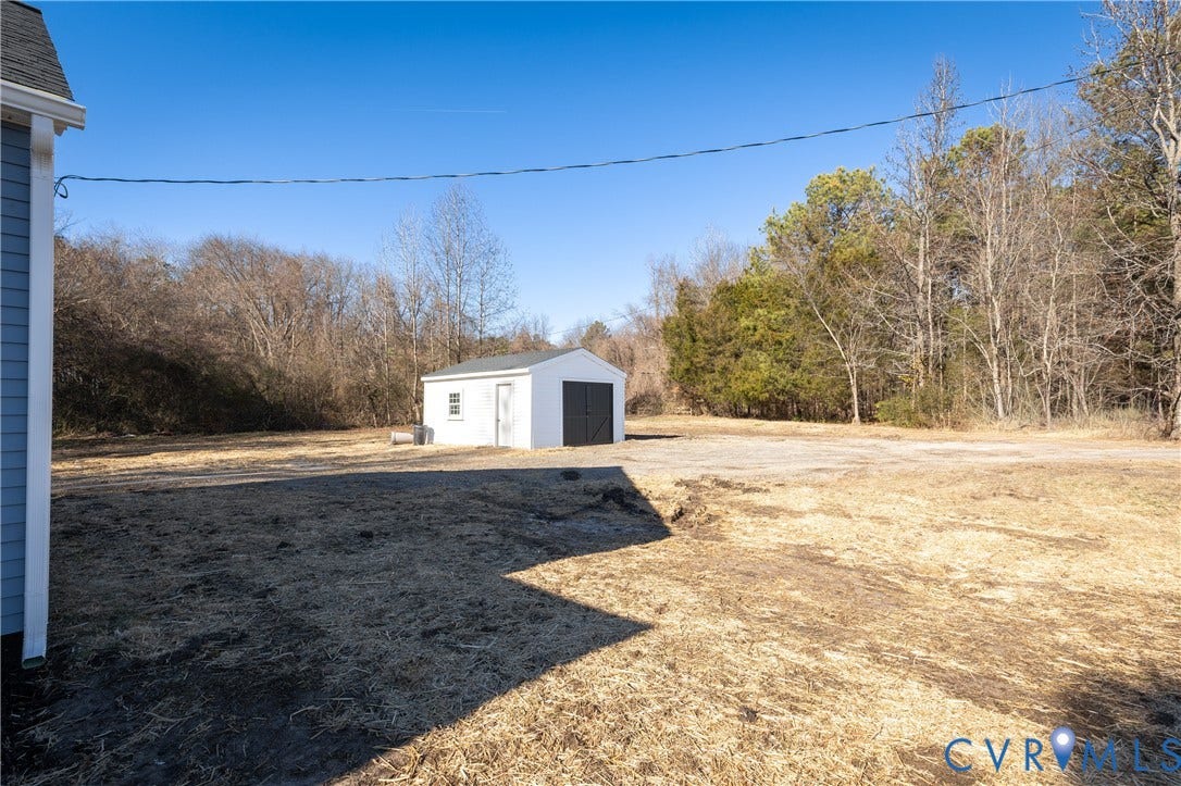 6280 Monahan Road, Henrico, VA 23231 Expansive rear grounds featuring a detached white storage structure with asphalt shingling and mature tree borders