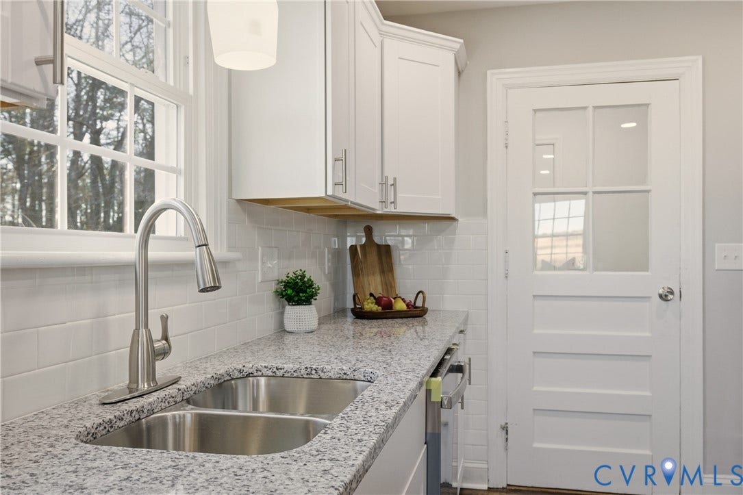 6280 Monahan Road, Henrico, VA 23231 Kitchen featuring white shaker-style cabinetry, speckled stone-finish countertops, a dual-basin stainless steel sink with a high-arch faucet, white subway tile backsplash, and a multi-pane glass door