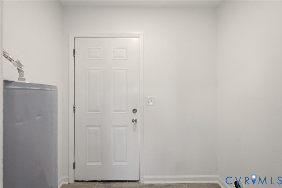 6280 Monahan Road, Henrico, VA 23231 Utility area featuring a six-panel door, neutral wall paint, and stone-finish tile flooring