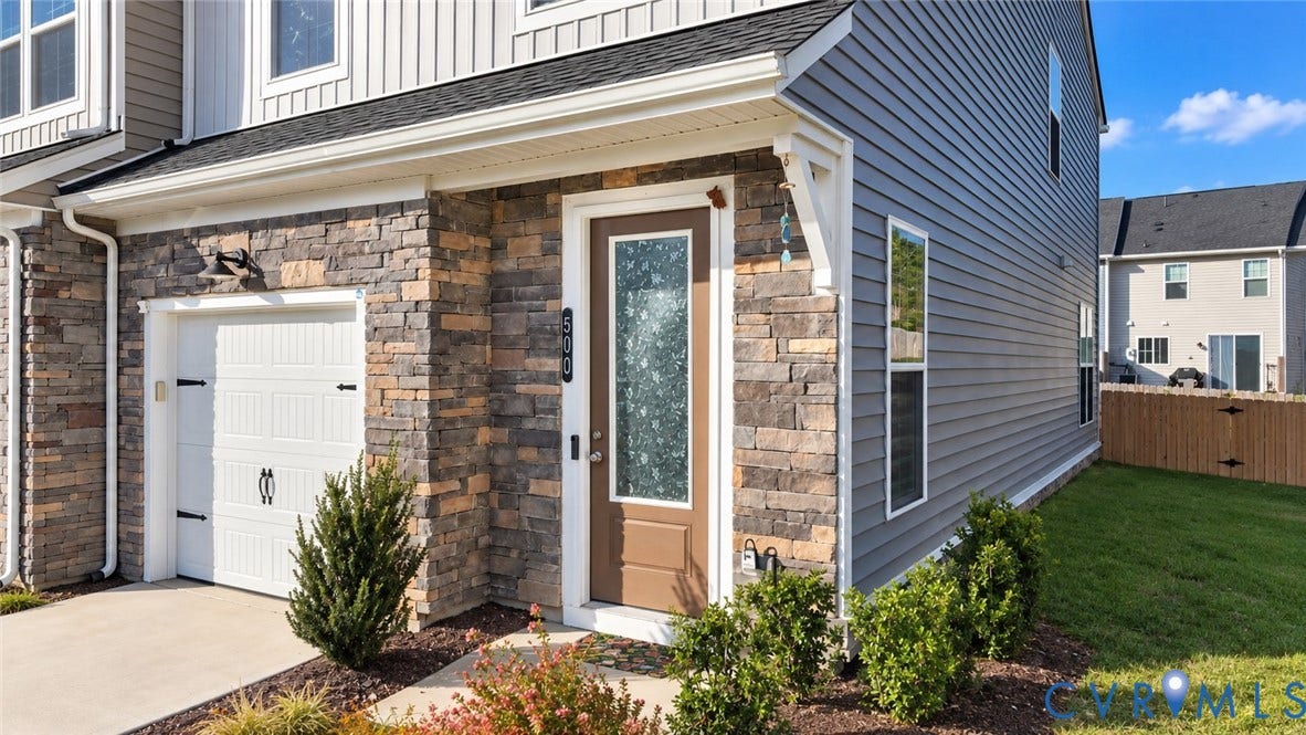 500 Rivanna Hill Way, Glen Allen, VA 23060 Exterior facade featuring mixed-material siding and stone veneer, single-car garage with carriage-style door, and a front entry door with a decorative glass panel