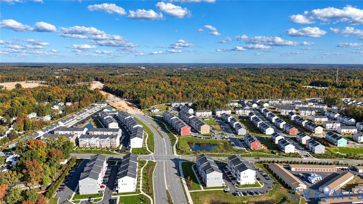 500 Rivanna Hill Way, Glen Allen, VA 23060 Aerial perspective of a multi-unit residential community featuring multi-story siding exteriors, paved street infrastructure, integrated pond, and expansive woodland surroundings