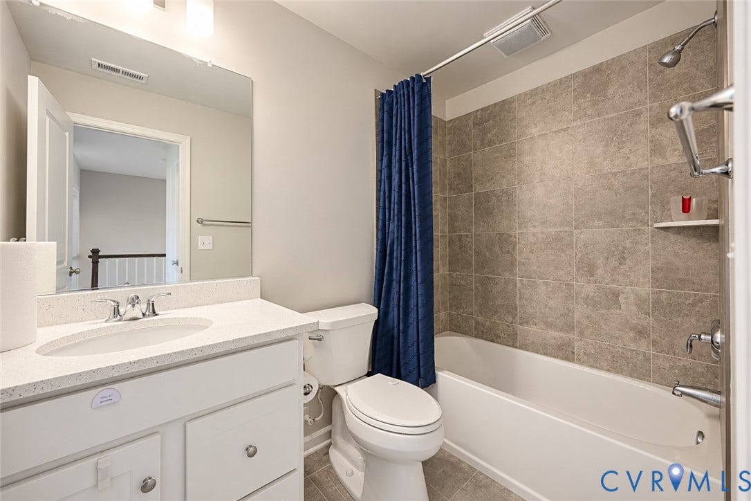 500 Rivanna Hill Way, Glen Allen, VA 23060 Bathroom featuring a vanity with a light-toned solid surface countertop and undermount sink, ceramic tile shower surround, and a large wall-mounted mirror