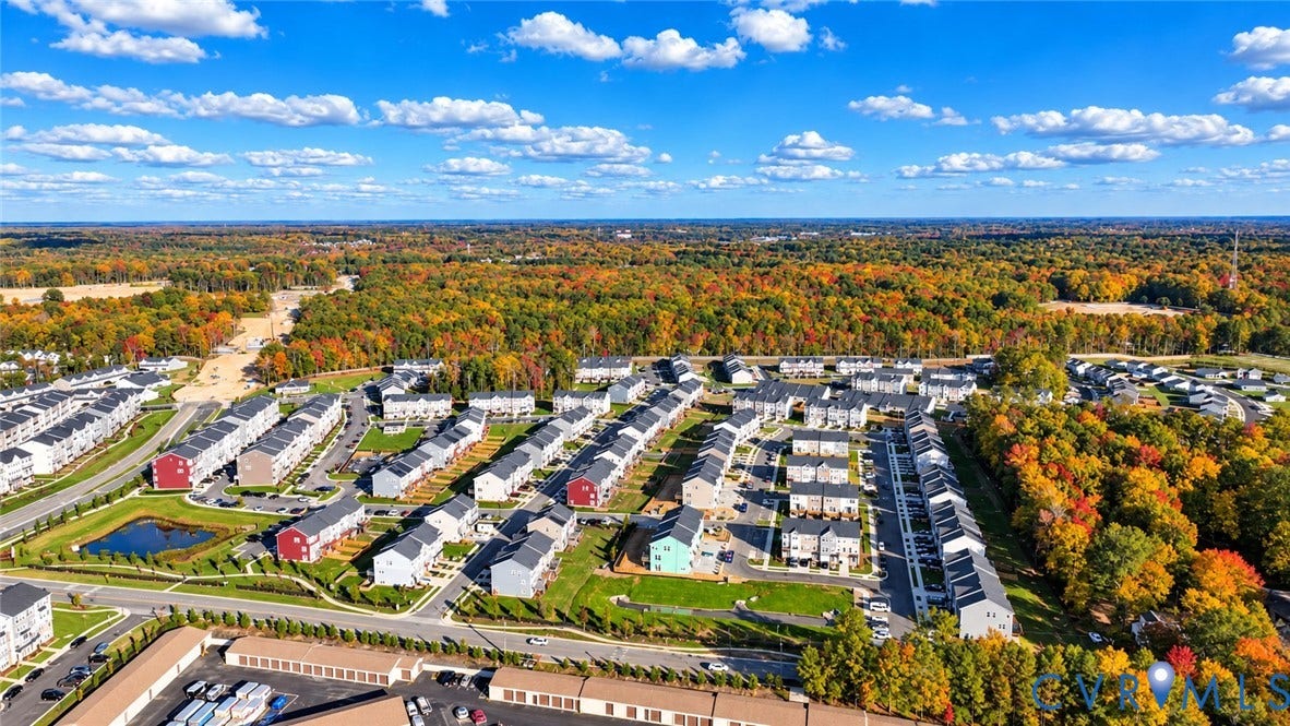 500 Rivanna Hill Way, Glen Allen, VA 23060 Aerial view of residential community featuring multi-unit buildings, paved streets, detention pond, and surrounding wooded area